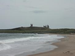 P2002A070043	Dunstanburgh Castle, with a loose boat being tossed around in the surf. 