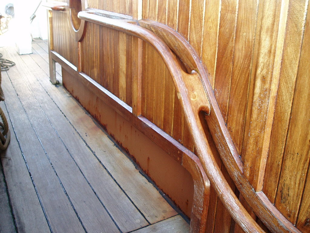 The curved handrail leading towards the stern of the ship.