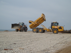 P20092260087	A dumper truck and digger on the beach.